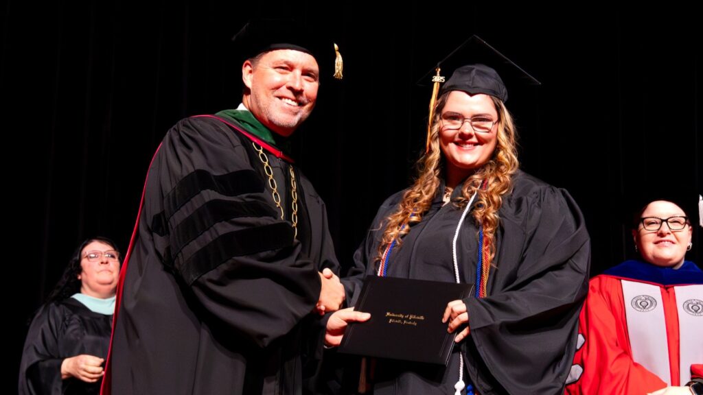 New graduate Haley McKinney accepts her diploma from UPike President Burton J. Webb. 
