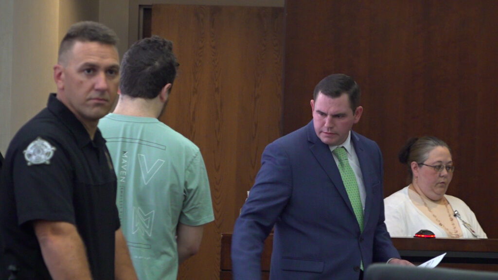 Attorney Randy Martin O'Neal, standing right, instructs his client, M.K. McKinney, where to sit during his arraignment July 31.