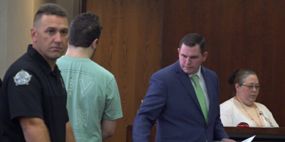Attorney Randy Martin O'Neal, standing right, instructs his client, M.K. McKinney, where to sit during his arraignment July 31.