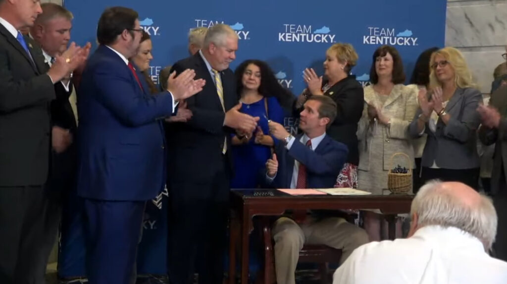Gov. Andy Beshear presents the pen he used to sign the bill to state Rep. John Blanton, who was the primary sponsor of the flood-relief package.