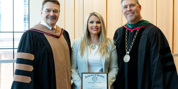 UPike President Dr. Burton Webb and Dr. Howard Roberts honor Whitesburg Mayor Tiffany Craft with the Baird Family Service Award.